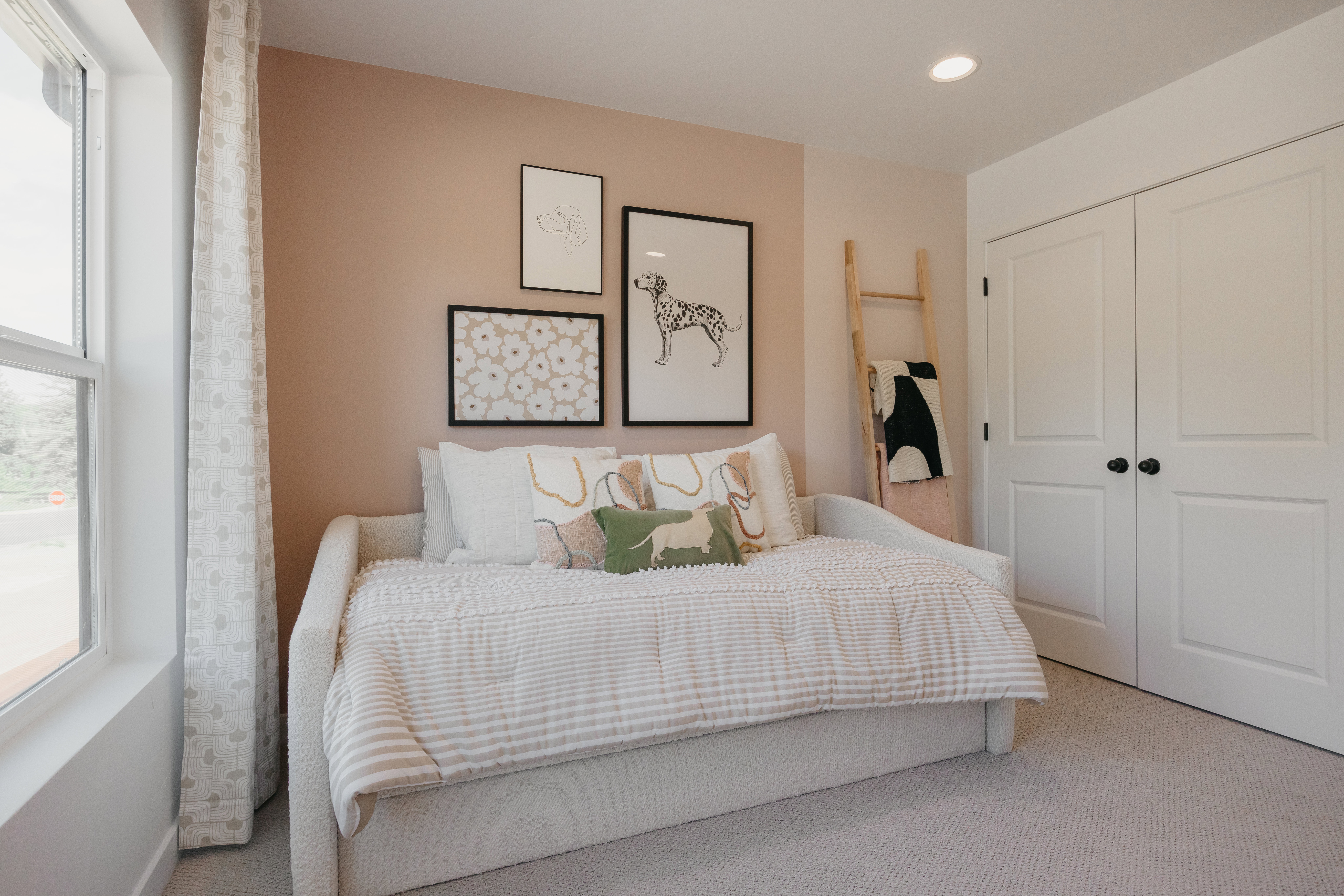 Light-filled room featuring a large window with patterned drapes, plush carpet flooring, recessed lighting, and a double-door closet with black hardware