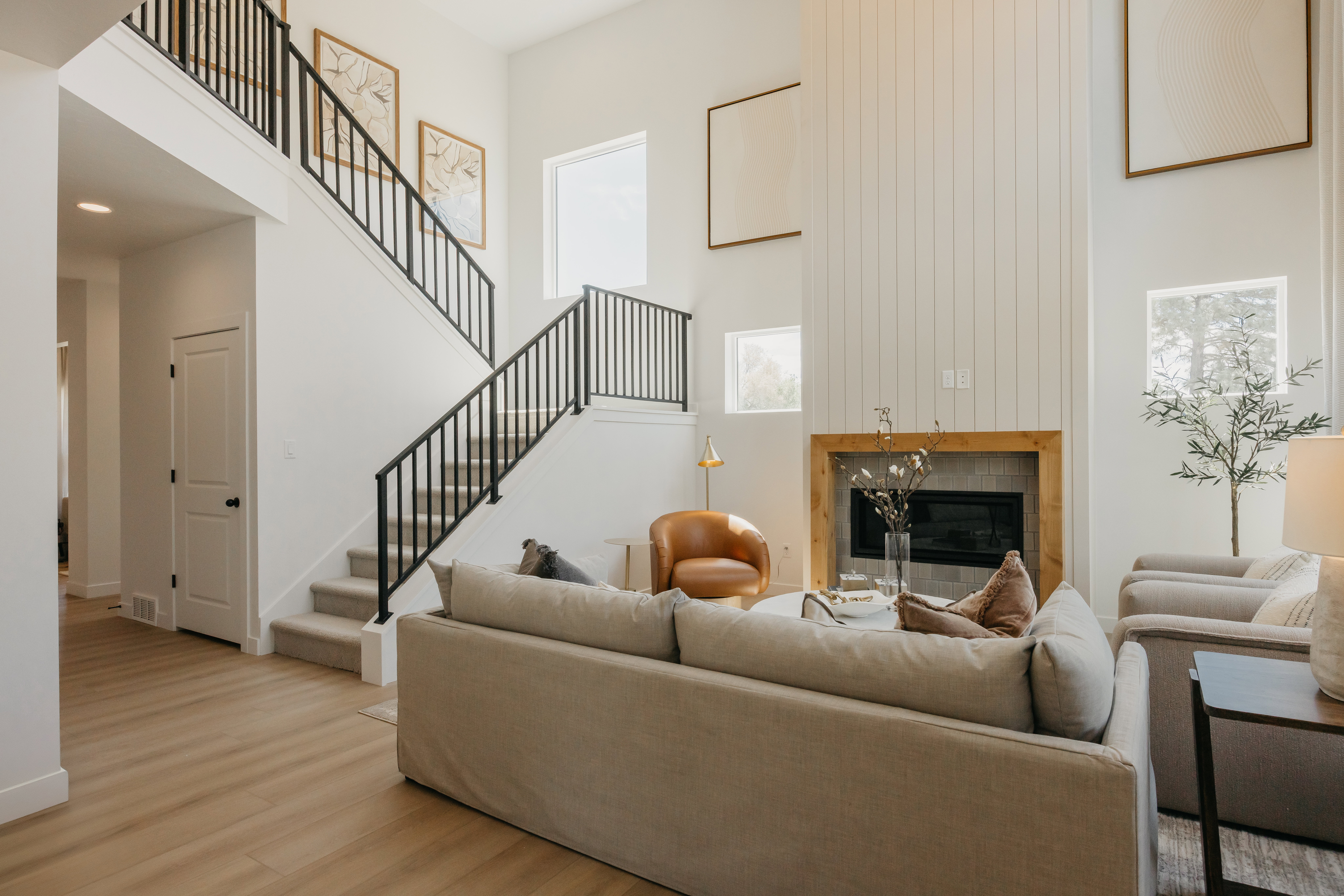 Two-story living area featuring a fireplace with a wood surround and tile hearth, a high ceiling with vertical paneling, and an open-tread staircase with black iron railings