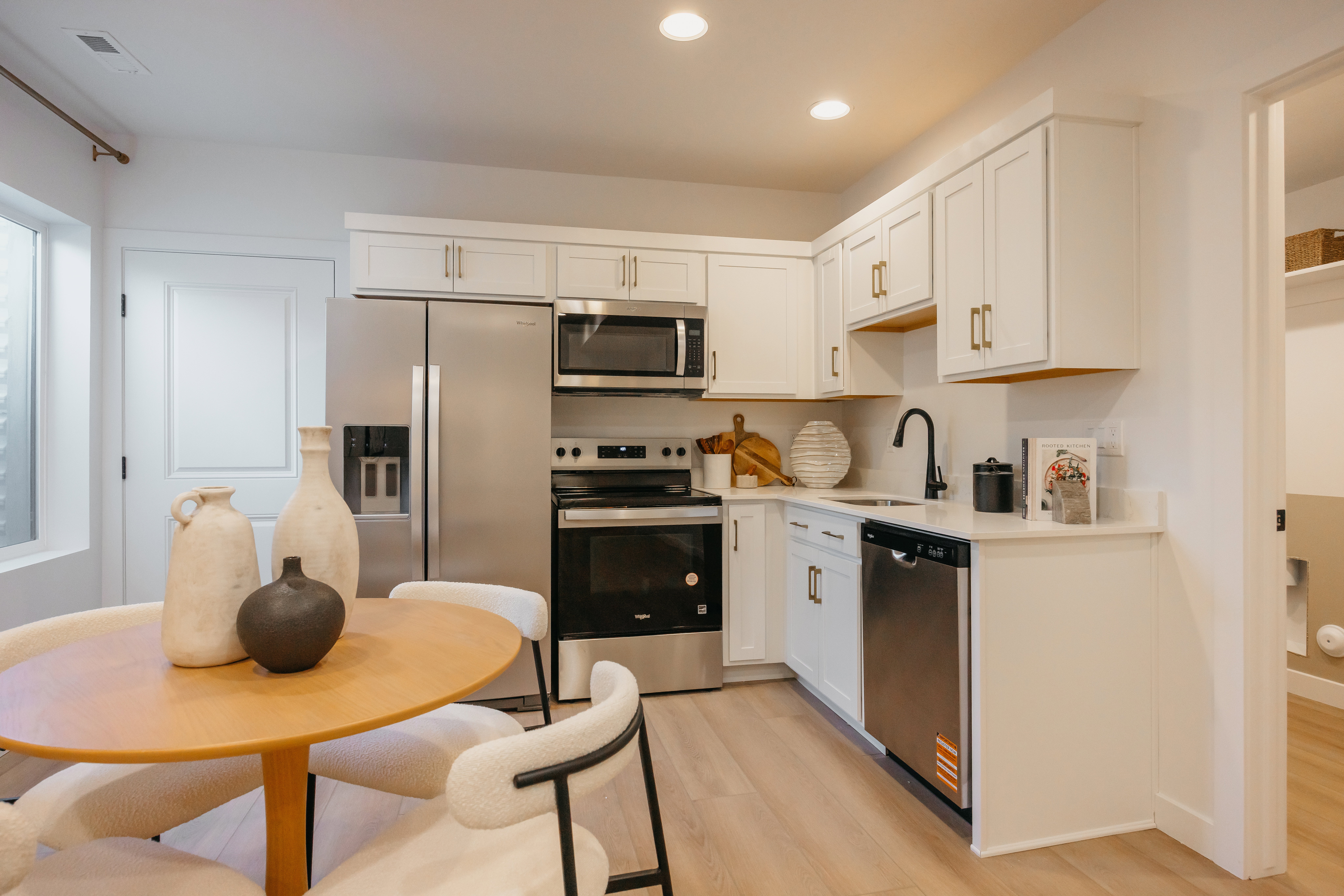Modern kitchen featuring stainless steel appliances, white cabinetry with gold-tone hardware, and a black faucet