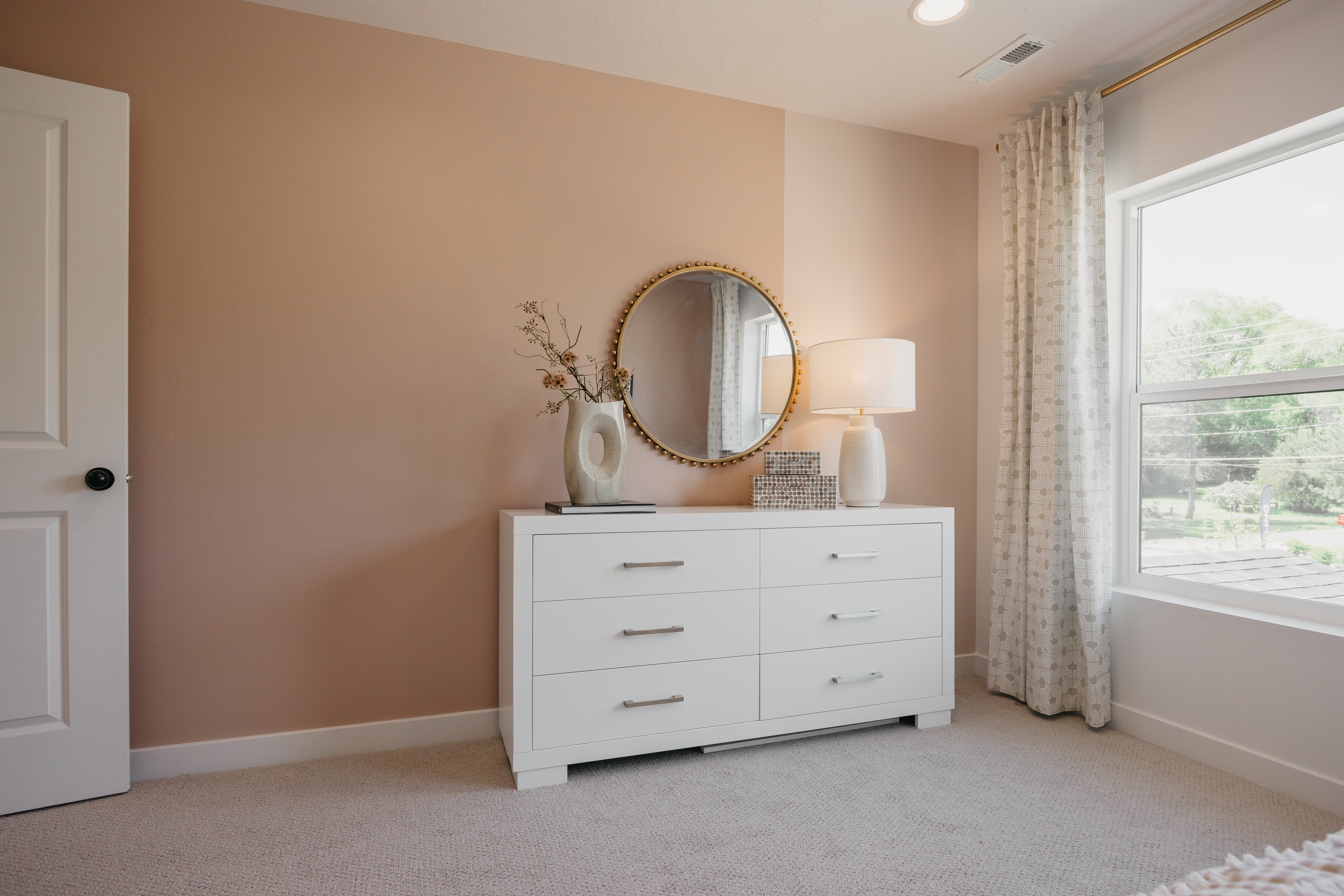 Spacious room featuring neutral wall tones, plush carpeting, a large window, recessed lighting, and a solid core door with black hardware