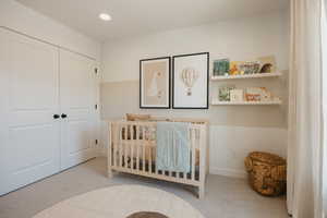Carpeted room featuring a double-door closet with black hardware, recessed lighting, and wall-mounted shelving