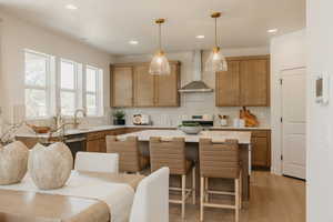 Open-concept kitchen featuring an island with seating, pendant lighting, stainless steel appliances, and wood-finish cabinetry