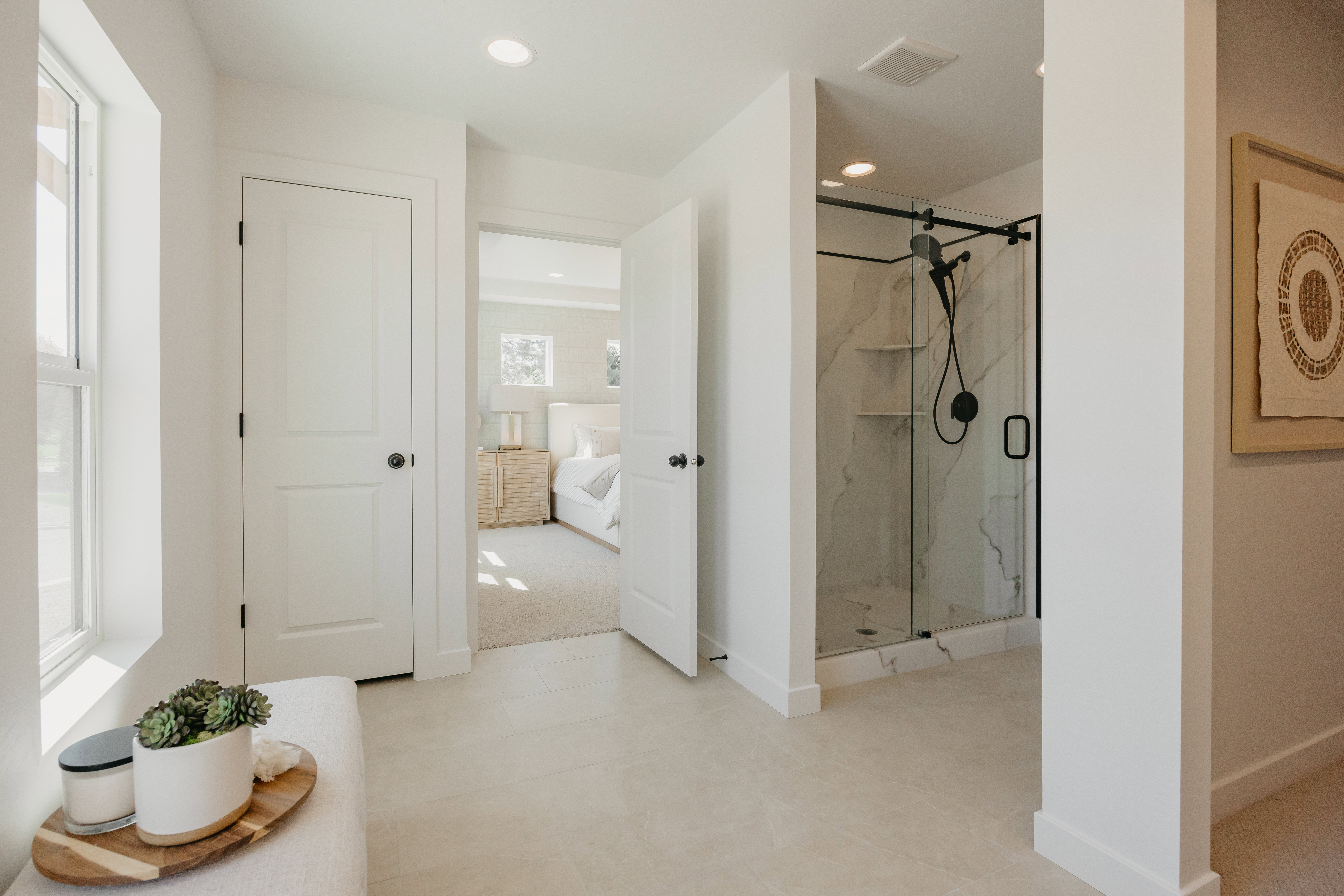 Spacious bathroom featuring light-toned tile flooring and a walk-in shower with a frameless glass enclosure