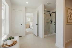 Spacious bathroom featuring light-toned tile flooring and a walk-in shower with a frameless glass enclosure