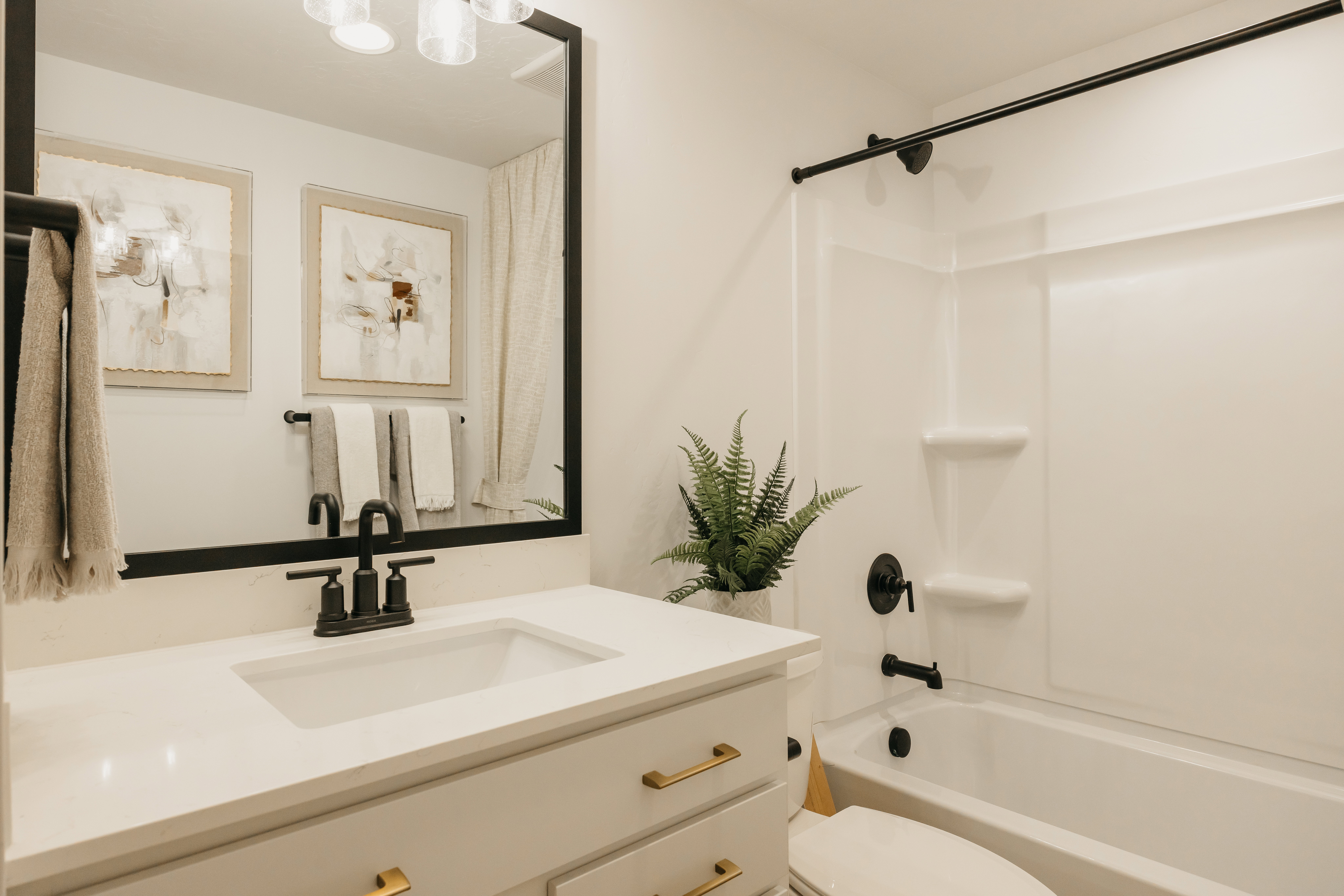 Bathroom featuring a white vanity with gold-tone hardware, a rectangular undermount sink, and a black-framed mirror