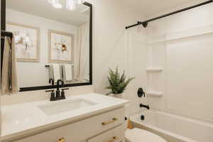 Bathroom featuring a white vanity with gold-tone hardware, a rectangular undermount sink, and a black-framed mirror