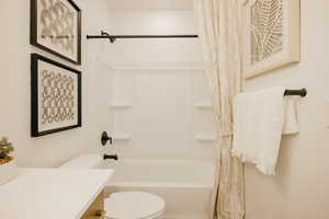 Bathroom featuring a white tub/shower combination with integrated shelving, matte black fixtures, and a white toilet