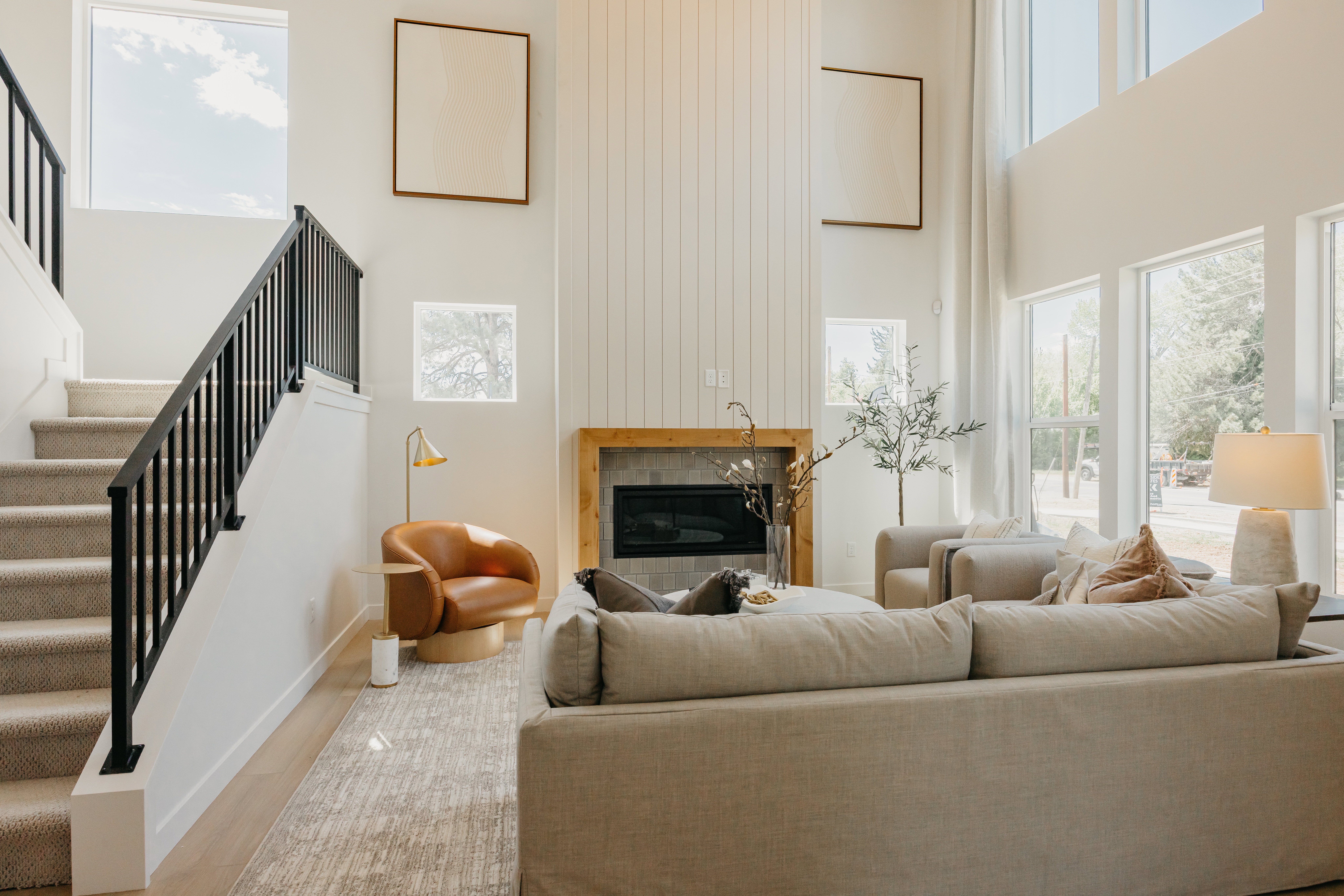 Two-story living area featuring a fireplace with a wood mantel, a shiplap accent wall, and wood-finish flooring