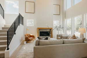 Two-story living area featuring a fireplace with a wood mantel, a shiplap accent wall, and wood-finish flooring