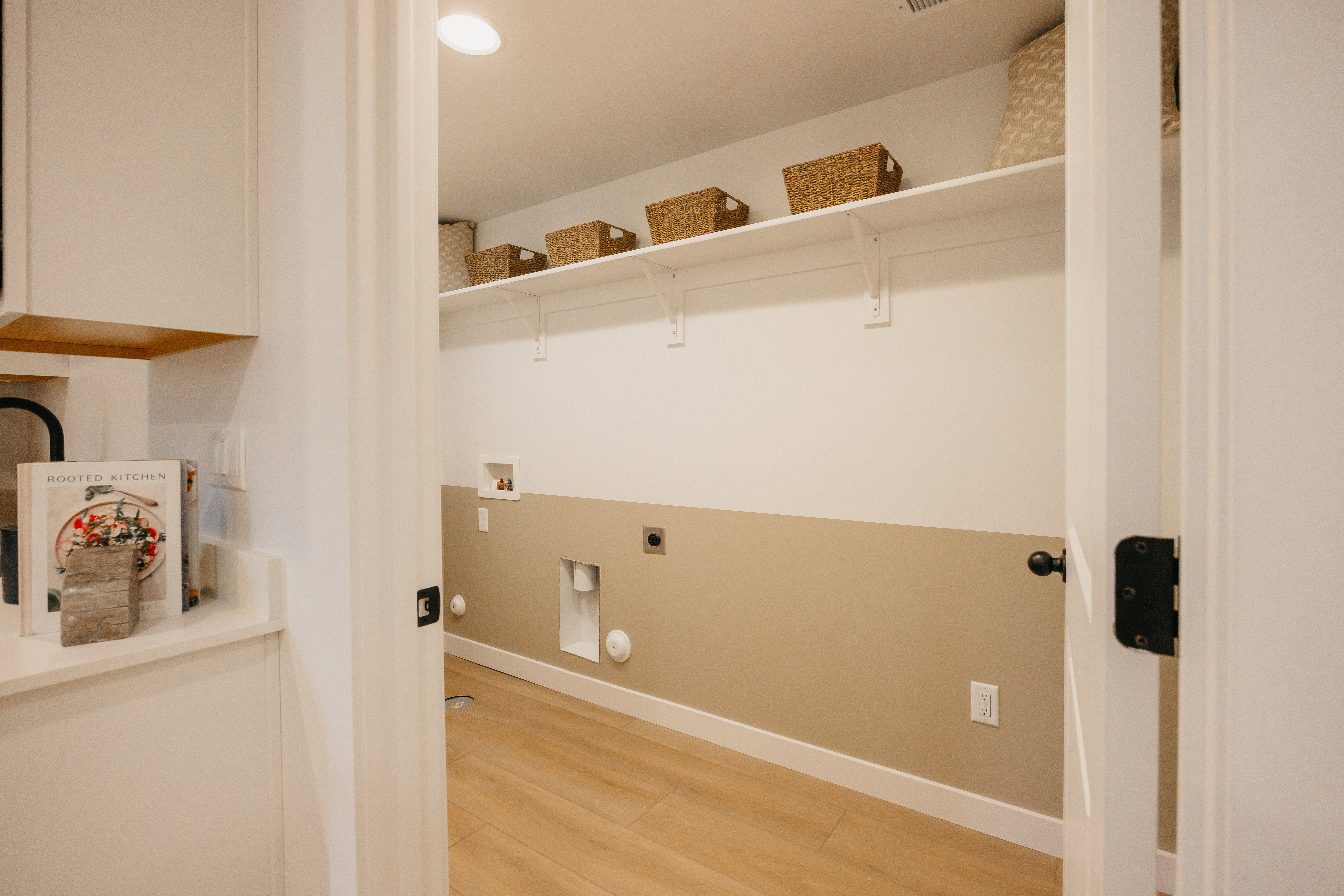 Dedicated utility room featuring wood-finish flooring, white trim, and a two-tone wall finish