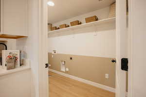 Dedicated utility room featuring wood-finish flooring, white trim, and a two-tone wall finish