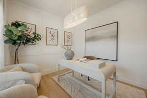 Office space featuring light wood-finish flooring, white panel accent wall, and recessed baseboards