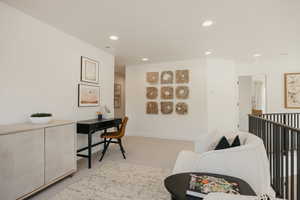 Loft area featuring recessed lighting, light-colored carpeting, and a dark metal railing