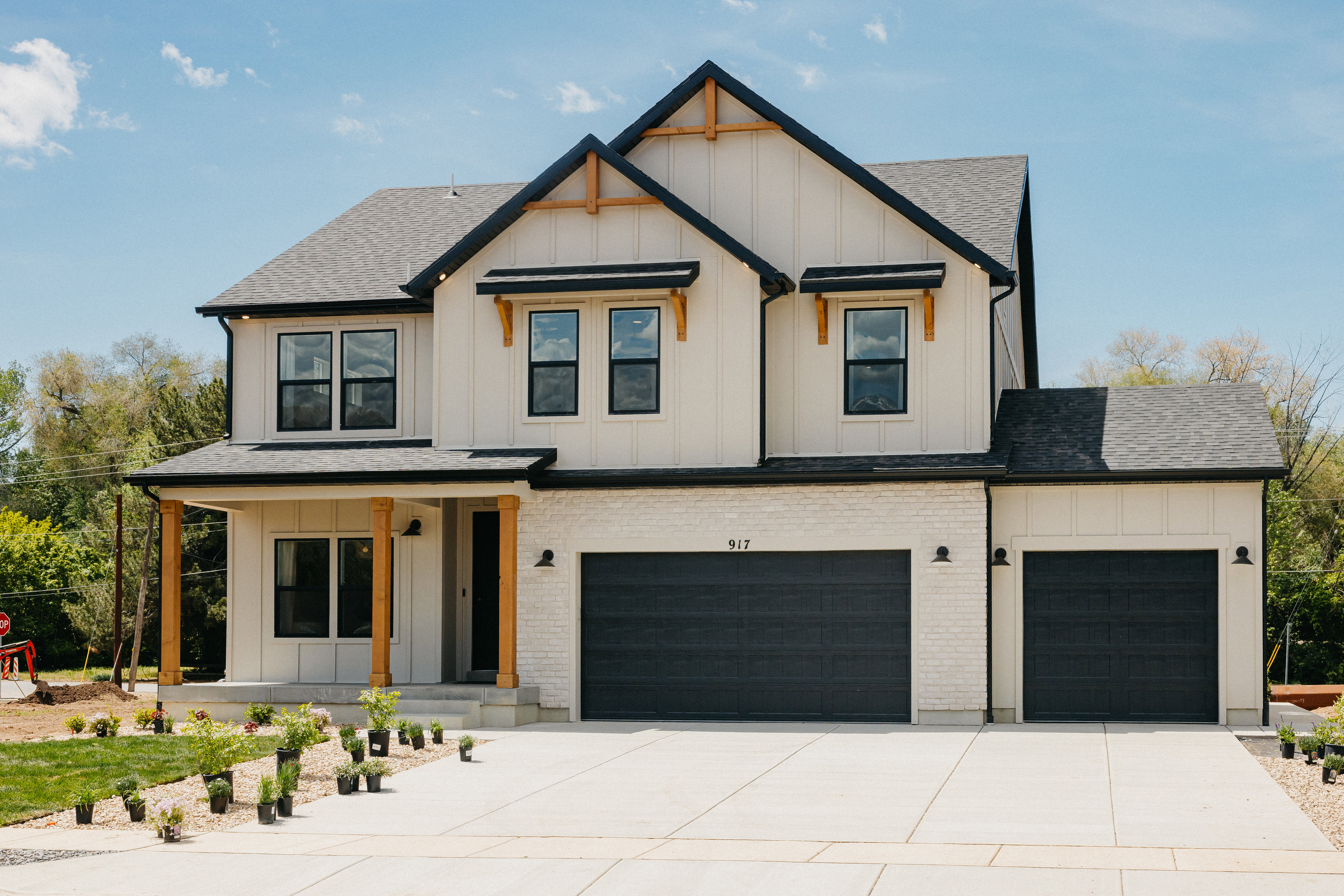 Modern farmhouse exterior featuring white board and batten siding, white brick accents, and a dark shingle roof