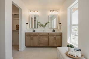 Dual vanity featuring neutral-toned wood cabinetry with matte black hardware, under-mount sinks, and light-toned countertops