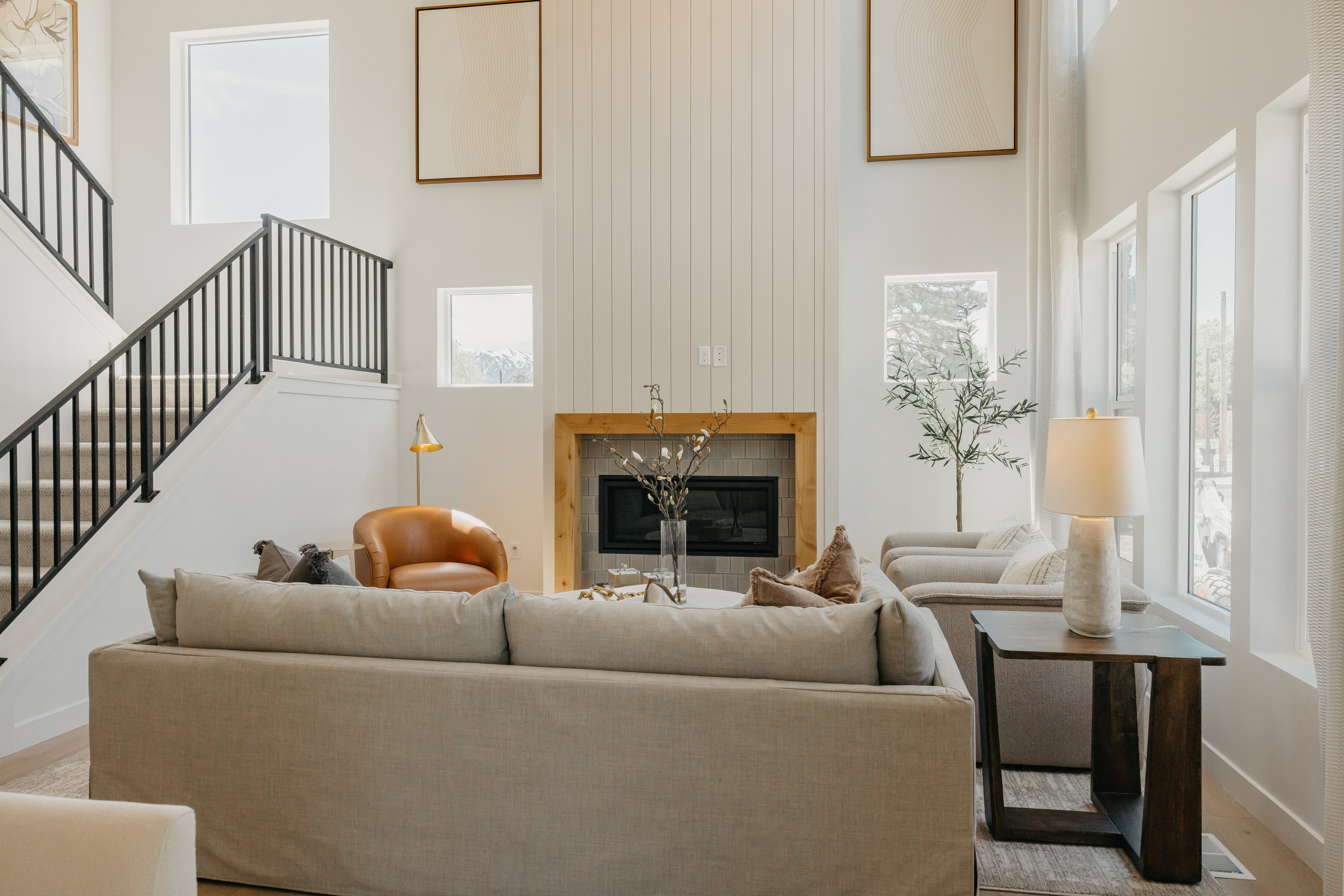 Spacious living area featuring a tall ceiling, a fireplace with a wood mantel, and expansive windows