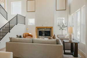 Spacious living area featuring a tall ceiling, a fireplace with a wood mantel, and expansive windows