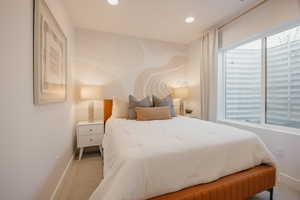 Spacious bedroom featuring recessed lighting, a large egress window, and a decorative wall accent