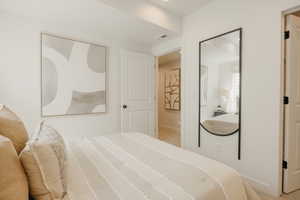 Clean bedroom space featuring light-colored walls and carpet flooring