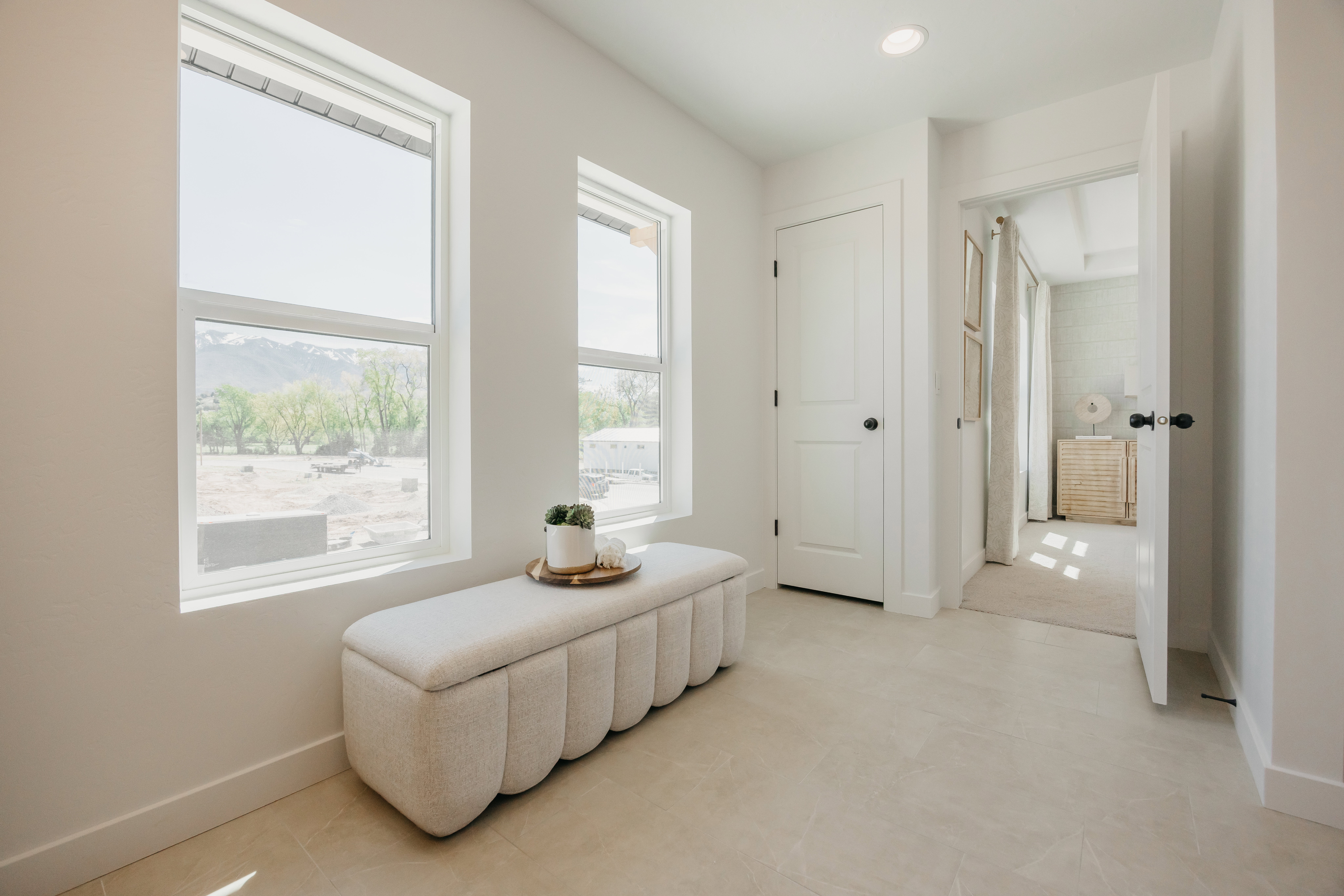 Hallway featuring two vertical windows, recessed lighting, and light-toned tile flooring