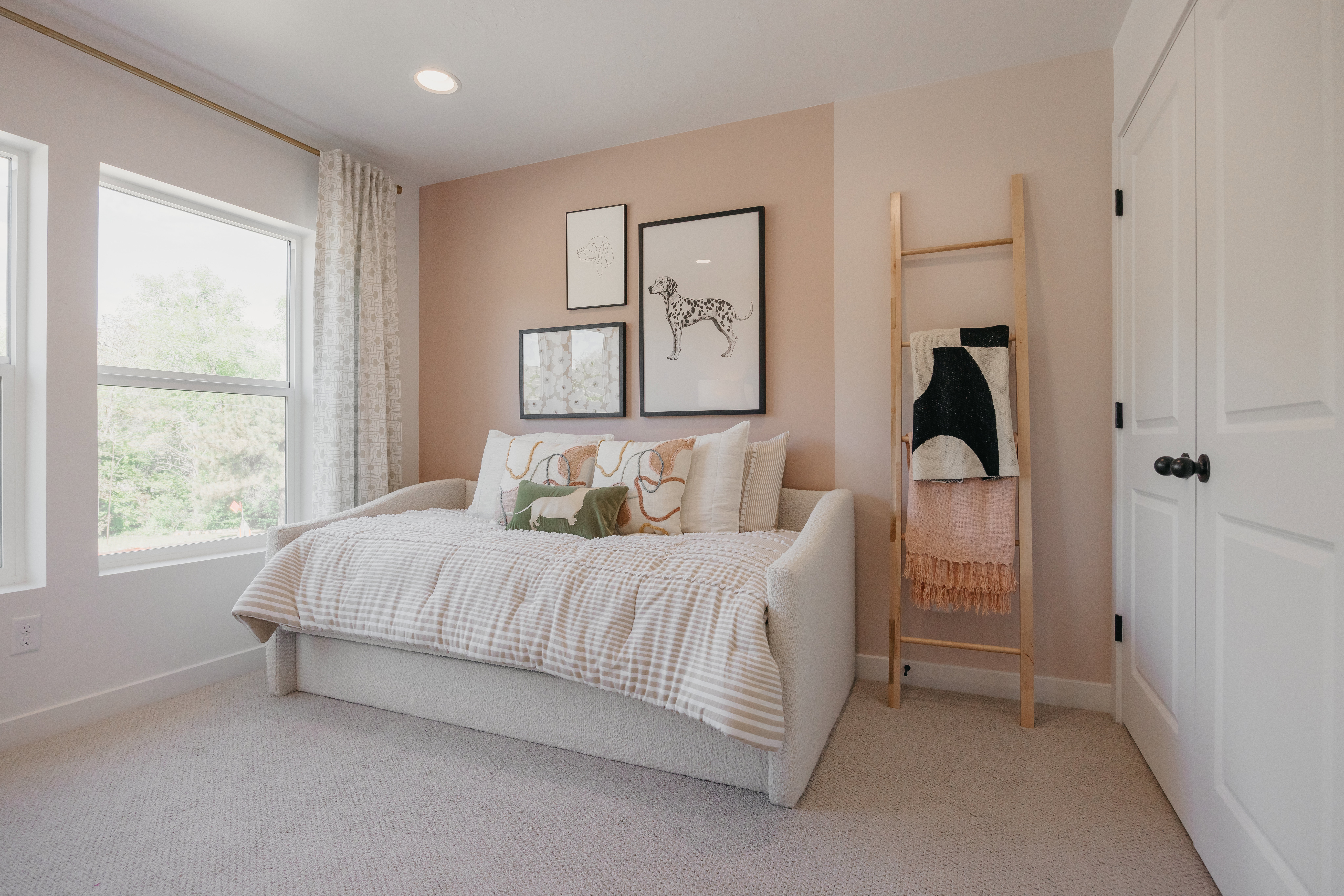 Recessed lighting illuminates a space featuring multiple windows with tree-lined scenery
