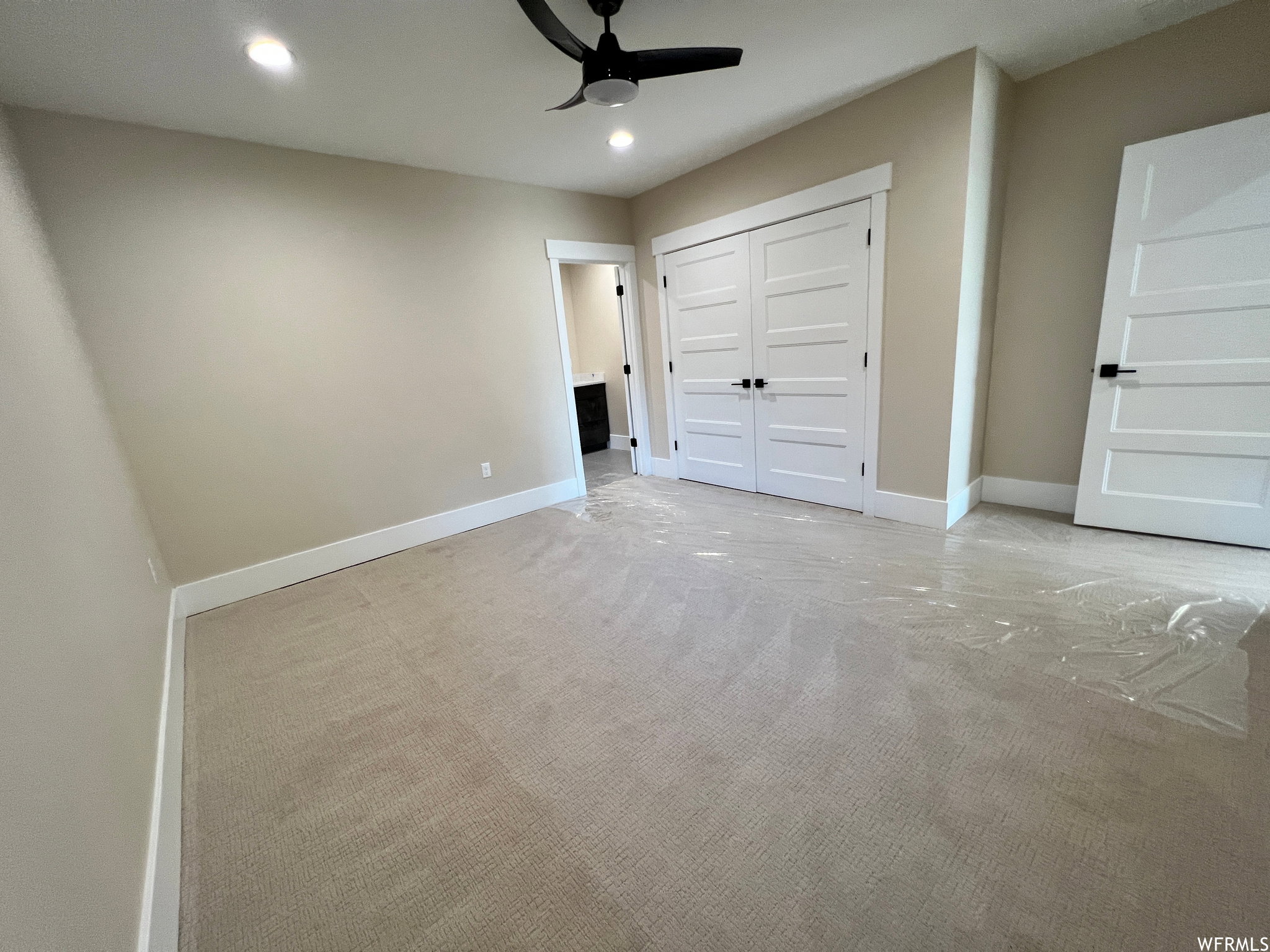 Carpeted room featuring recessed lighting, a ceiling fan, white baseboards, and a double-door closet with black hardware
