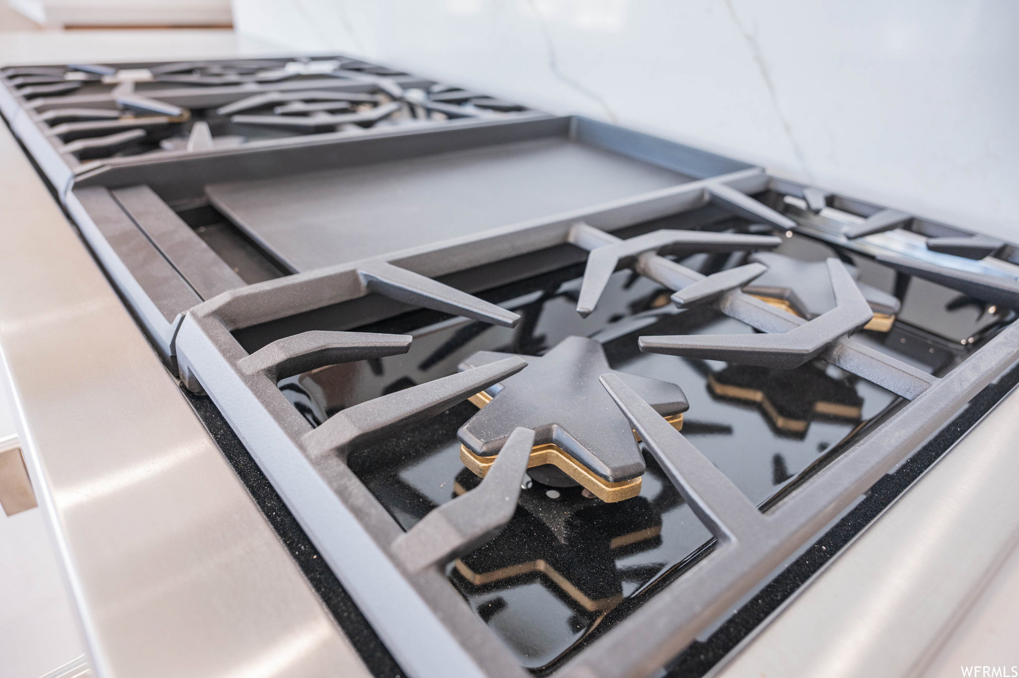 Professional-grade gas range with a stainless steel finish, cast iron grates, six burners, a griddle, and a polished black cooktop
