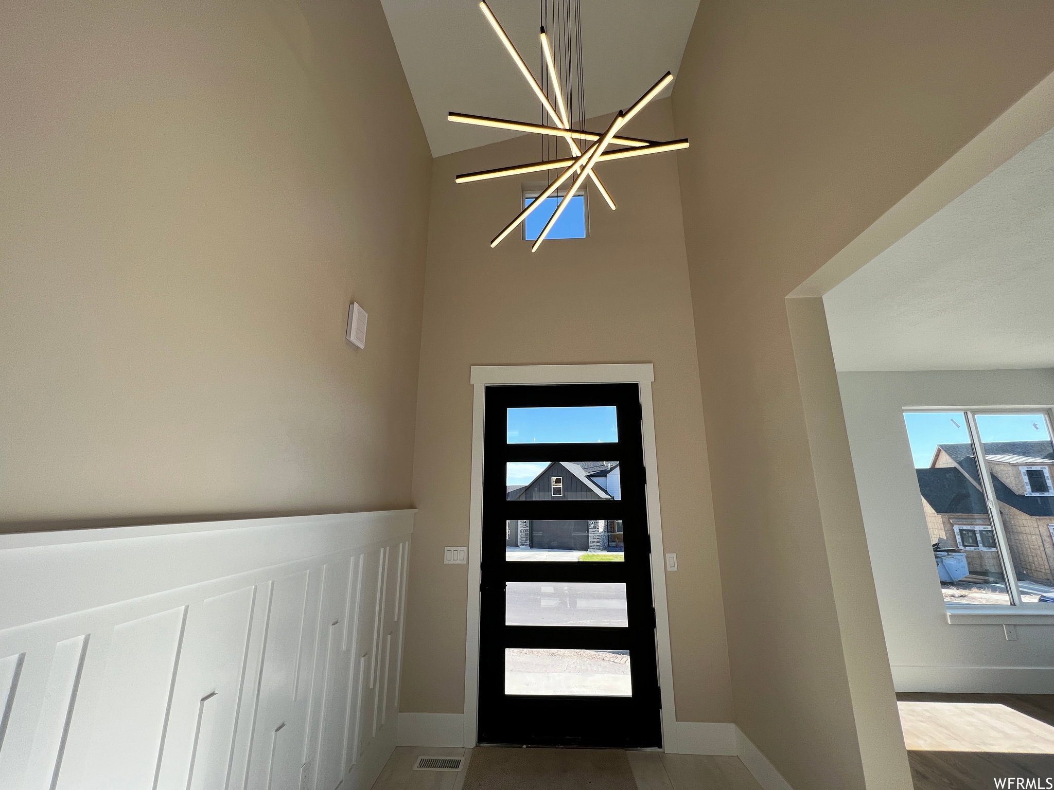 Two-story entryway featuring a contemporary chandelier, board and batten wainscoting, and a black front door with horizontal lites