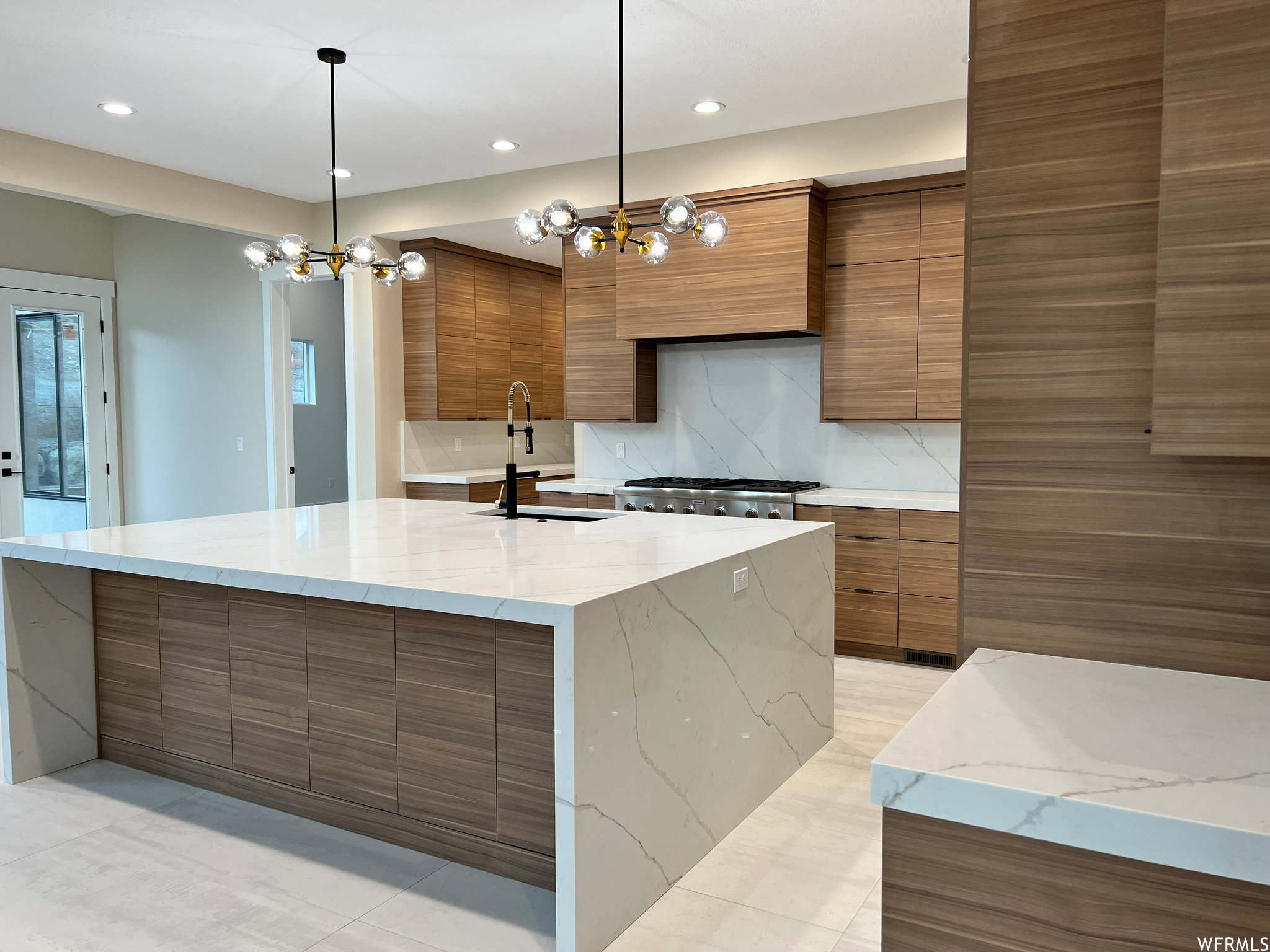 Expansive kitchen island featuring a waterfall-edge countertop and wood-finish paneling