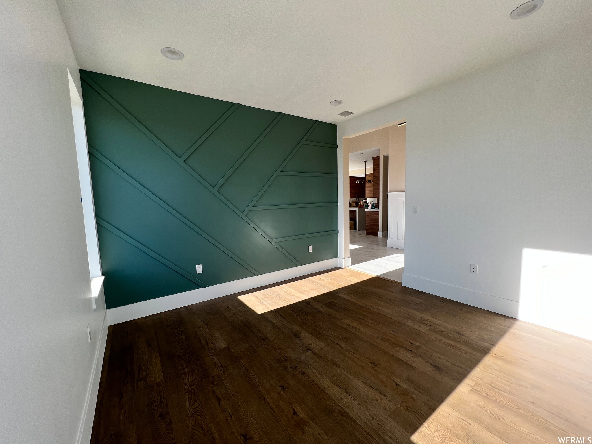 Accent wall with geometric trim detailing, wood-finish flooring, recessed lighting, and white baseboards
