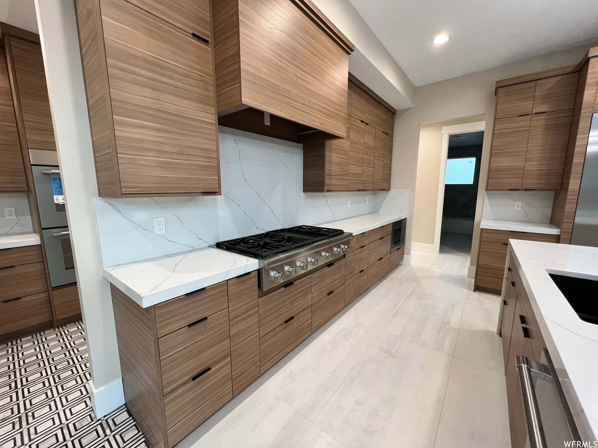 Gourmet kitchen featuring extensive wood-finish cabinetry, white countertops, a large professional-grade range, and a full-height backsplash