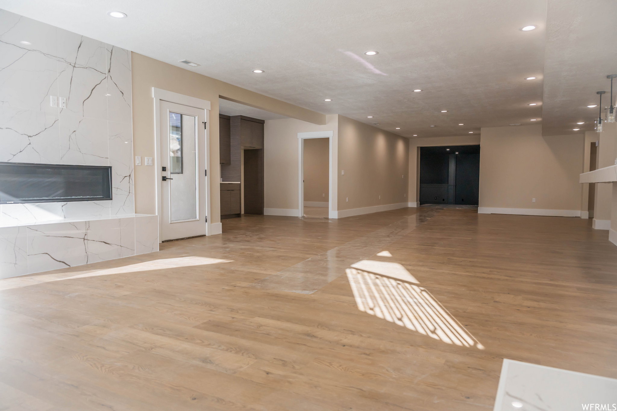 Spacious open-concept room featuring light wood-finish flooring and recessed lighting throughout