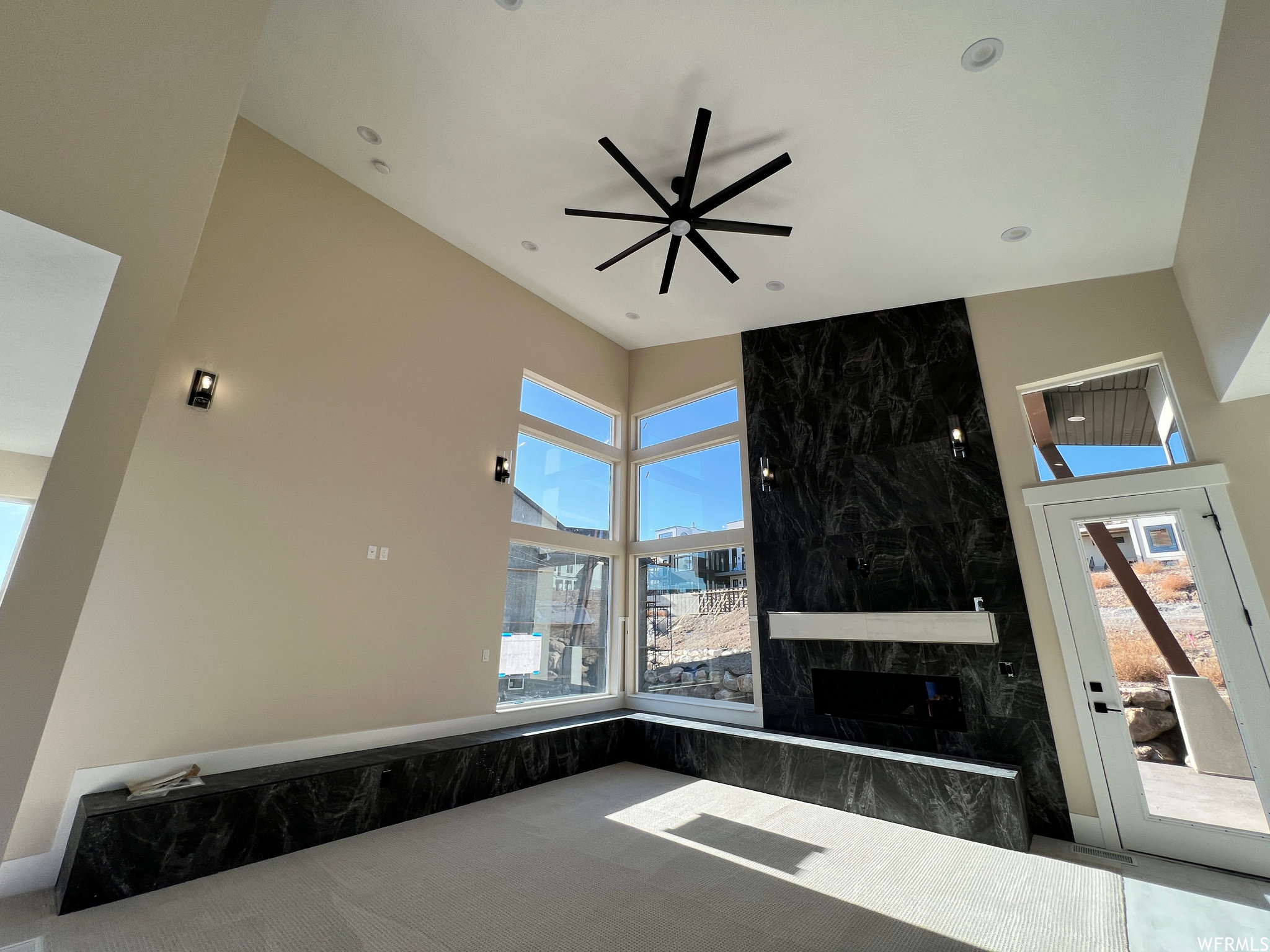 Two-story living area featuring a black marble-finish accent wall with a built-in fireplace, a matching marble-finish built-in bench, and a modern ceiling fan