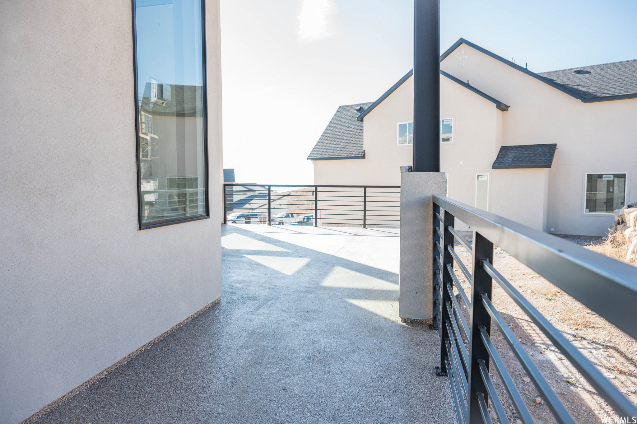 Spacious outdoor terrace with a speckled concrete surface and contemporary black metal railings
