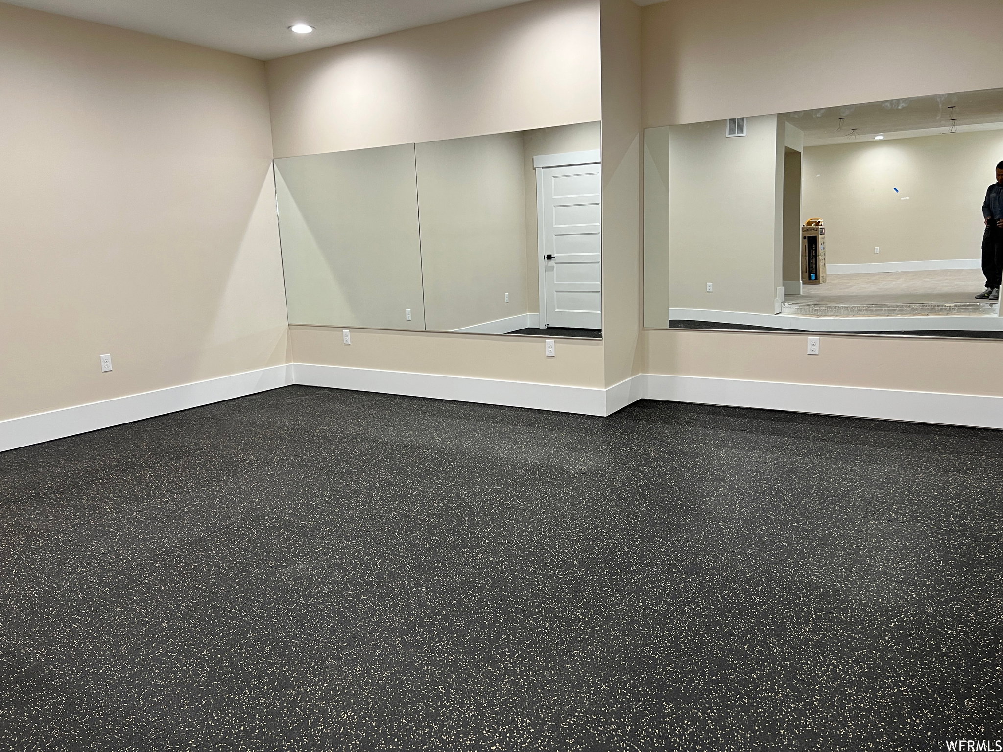 Room featuring speckled flooring, neutral wall paint, and white baseboards