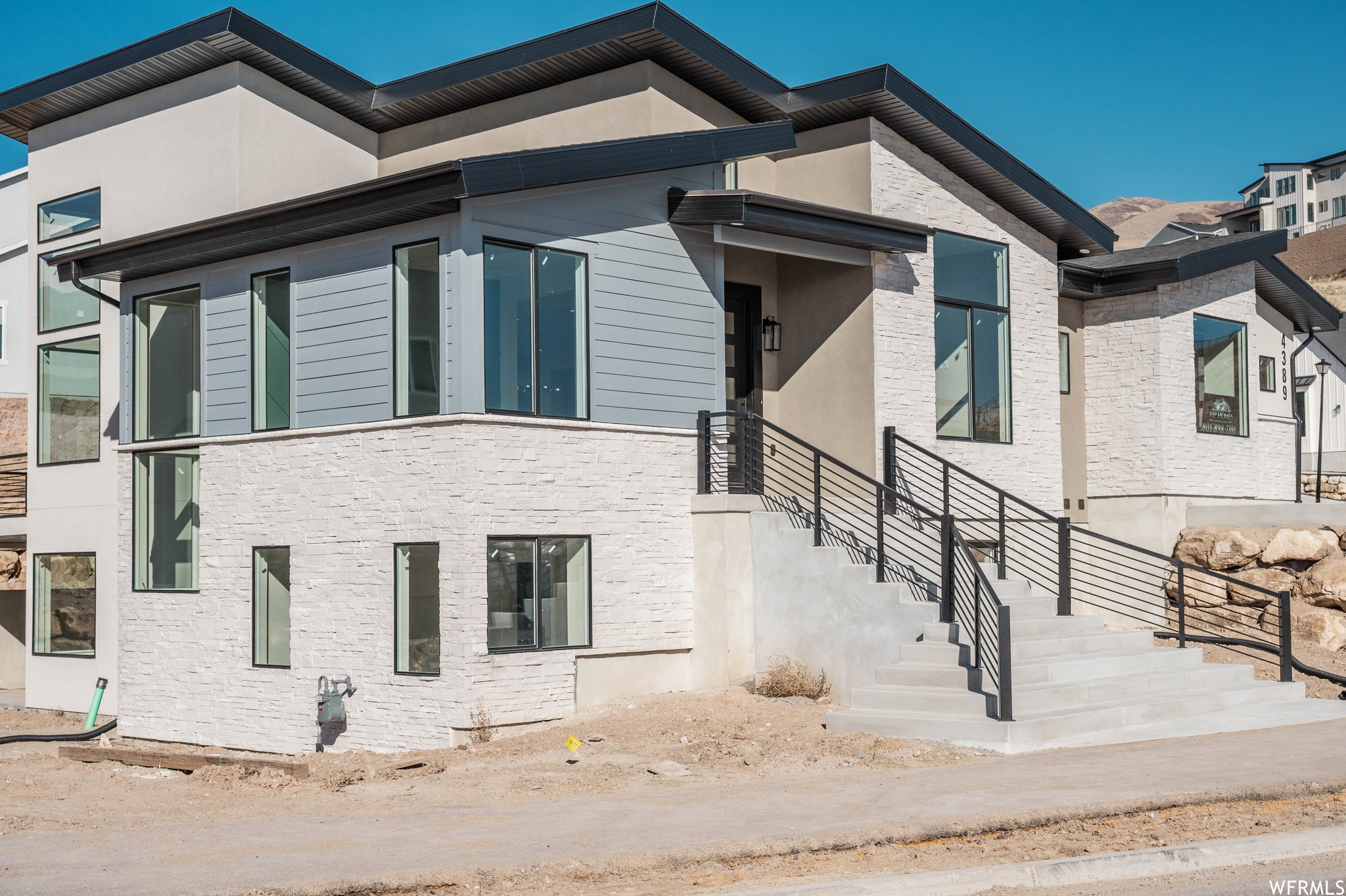 Contemporary multi-level exterior featuring light-colored stacked stone and light blue siding