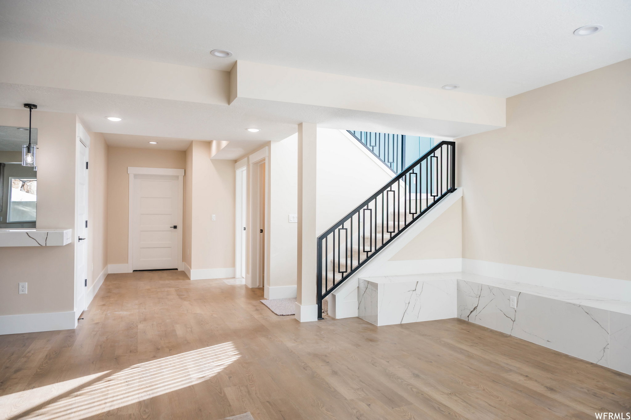 Open concept living area featuring wood-finish flooring, recessed lighting, and a contemporary staircase with a black metal railing