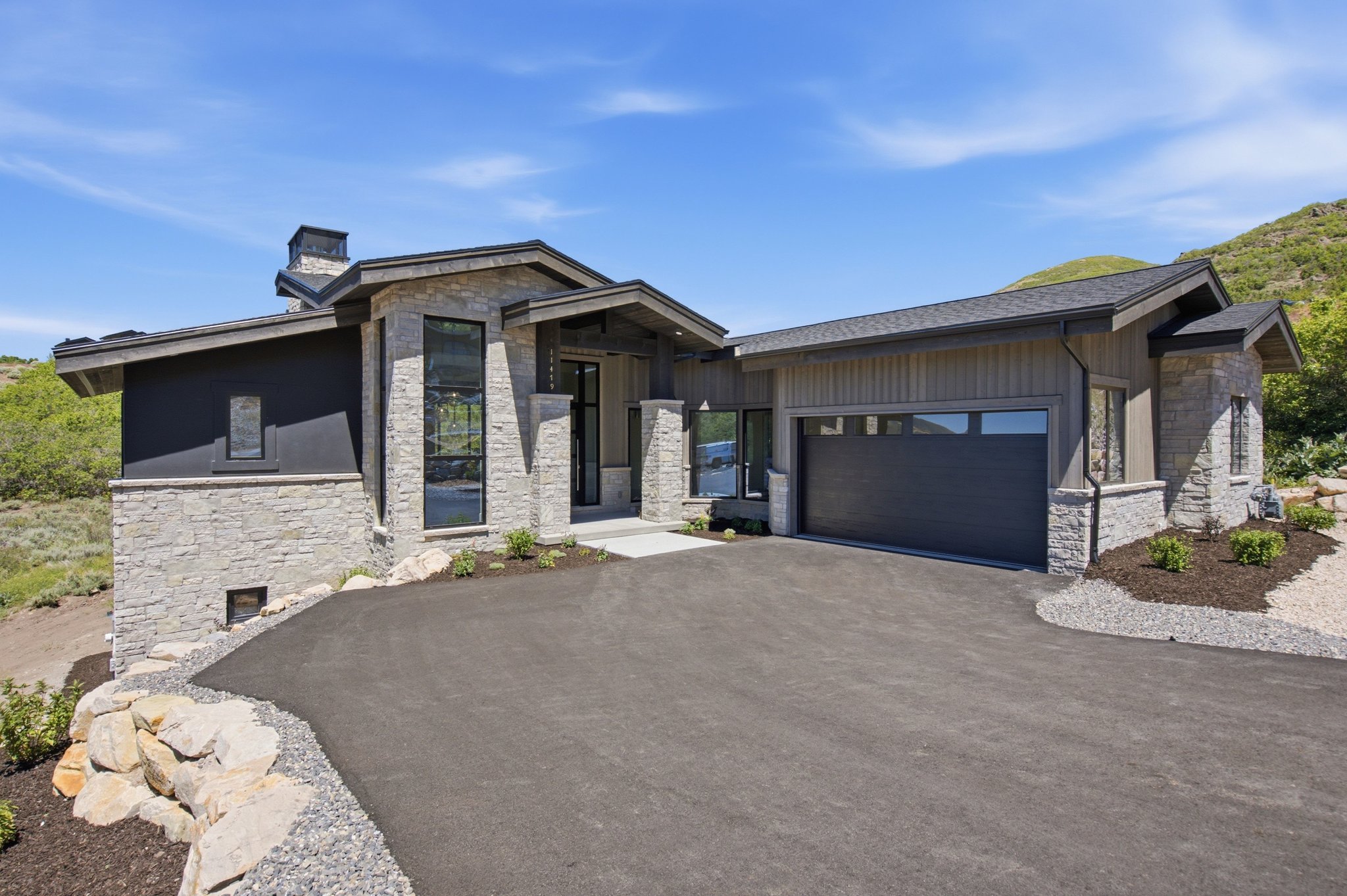Contemporary exterior featuring stone accents, vertical wood-finish siding, and dark stucco