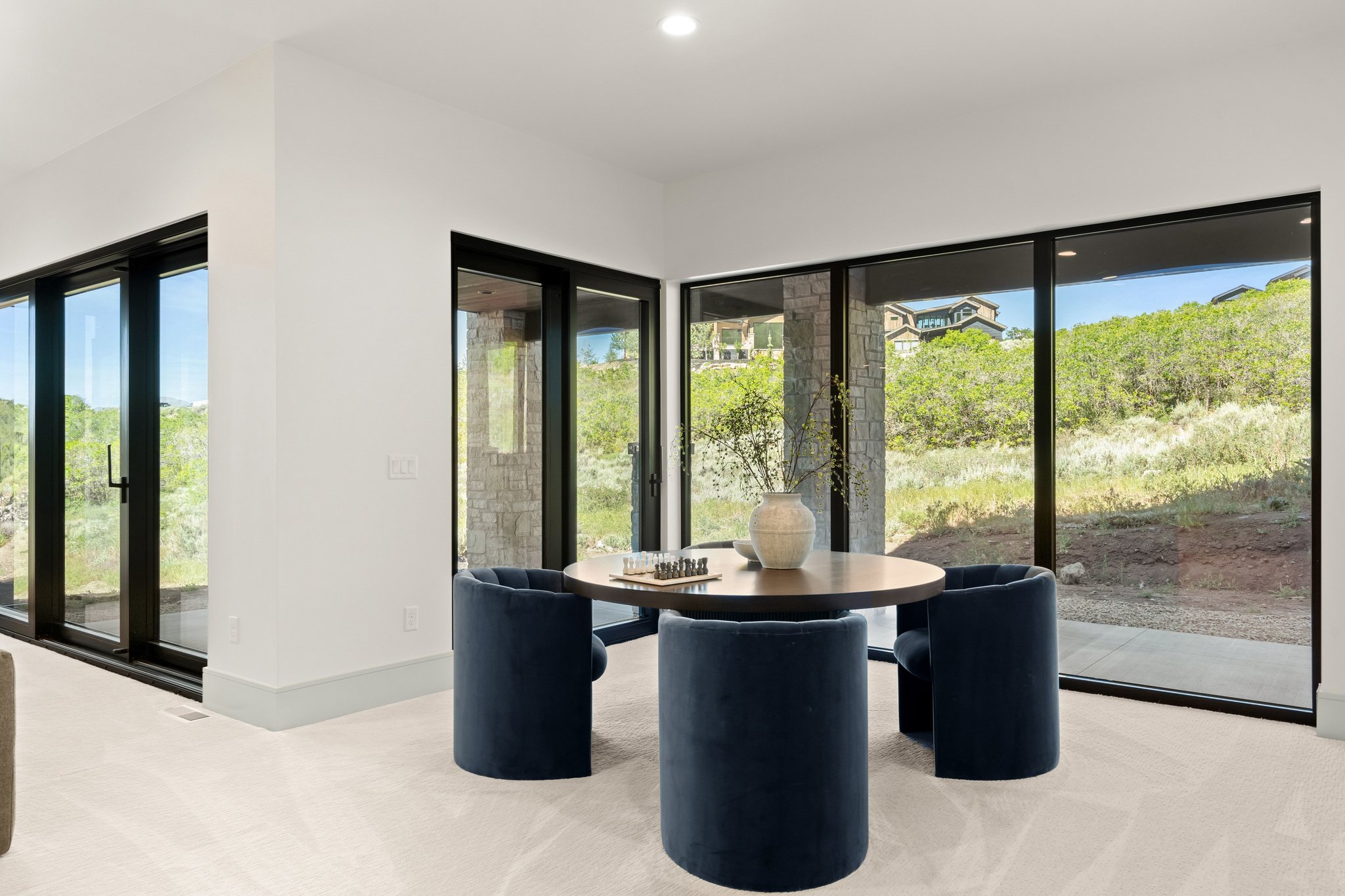 Expansive floor-to-ceiling windows with black frames, white walls, and light-colored carpeting throughout