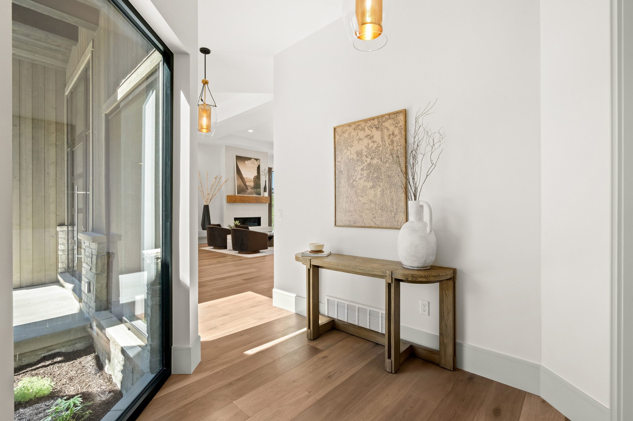 Wide plank wood-finish flooring extends through the entryway