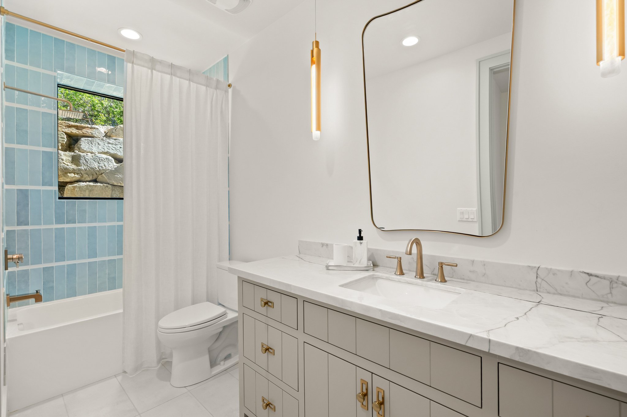 Contemporary bathroom featuring a vanity with a stone countertop, an undermount sink, and brass-finish fixtures