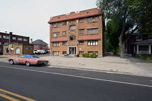 Brick multi-story building featuring a red tile roofline and arched entry