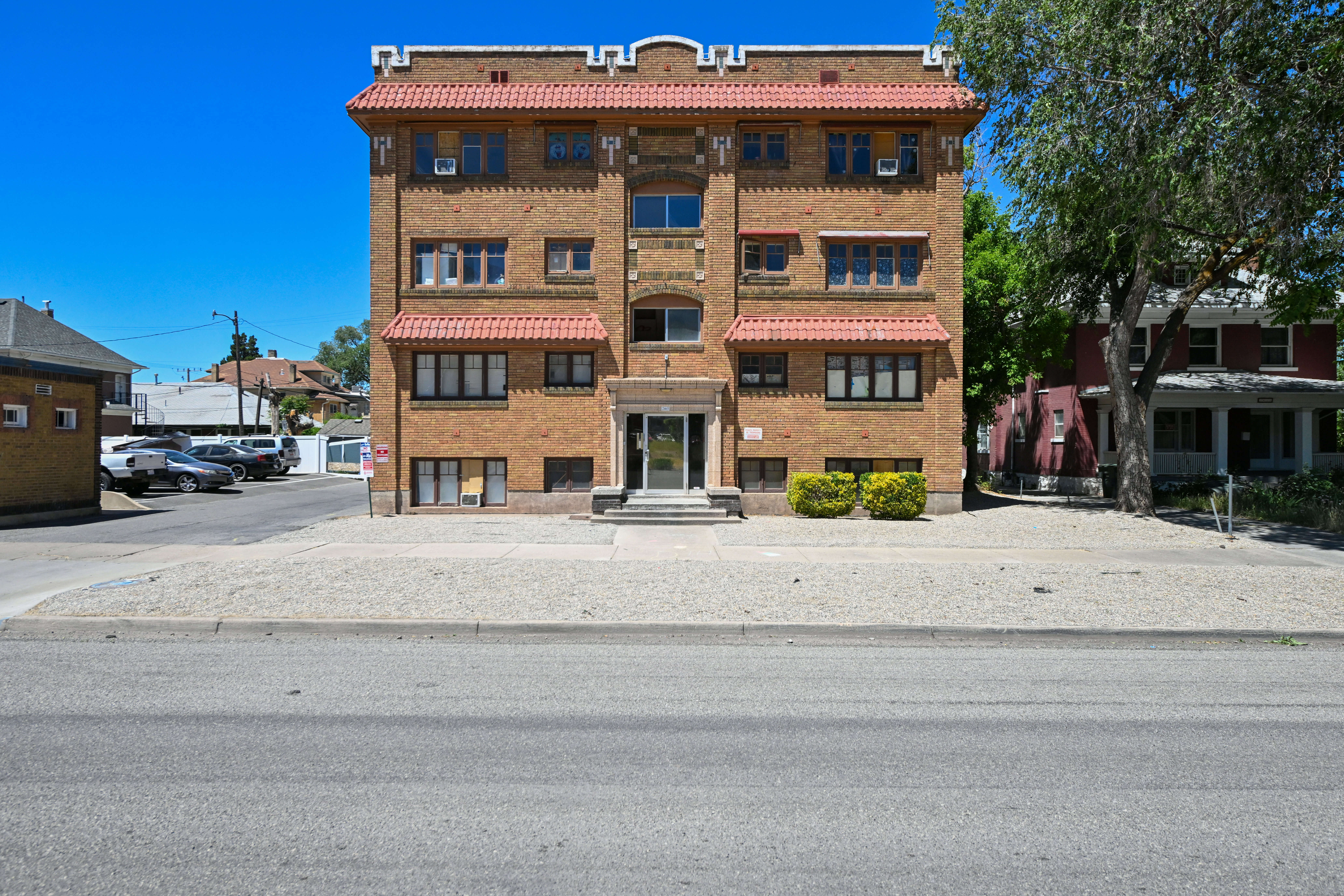 Brick facade multi-story building featuring decorative parapet walls and red tile awnings