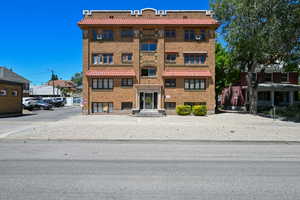 Brick facade multi-story building featuring decorative parapet walls and red tile awnings