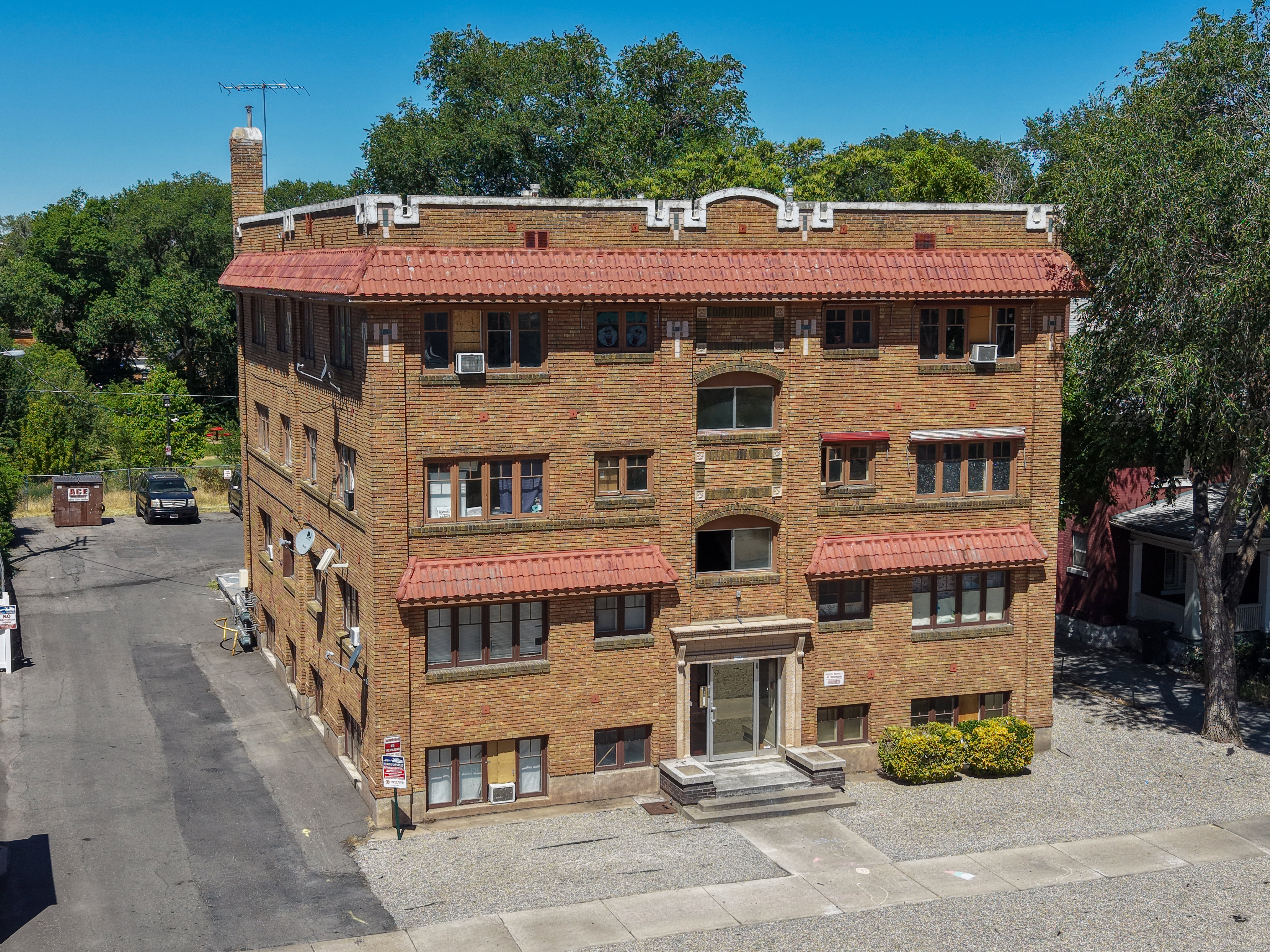 Brick apartment building featuring a red tile roof and multiple window awnings