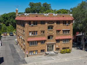 Brick apartment building featuring a red tile roof and multiple window awnings