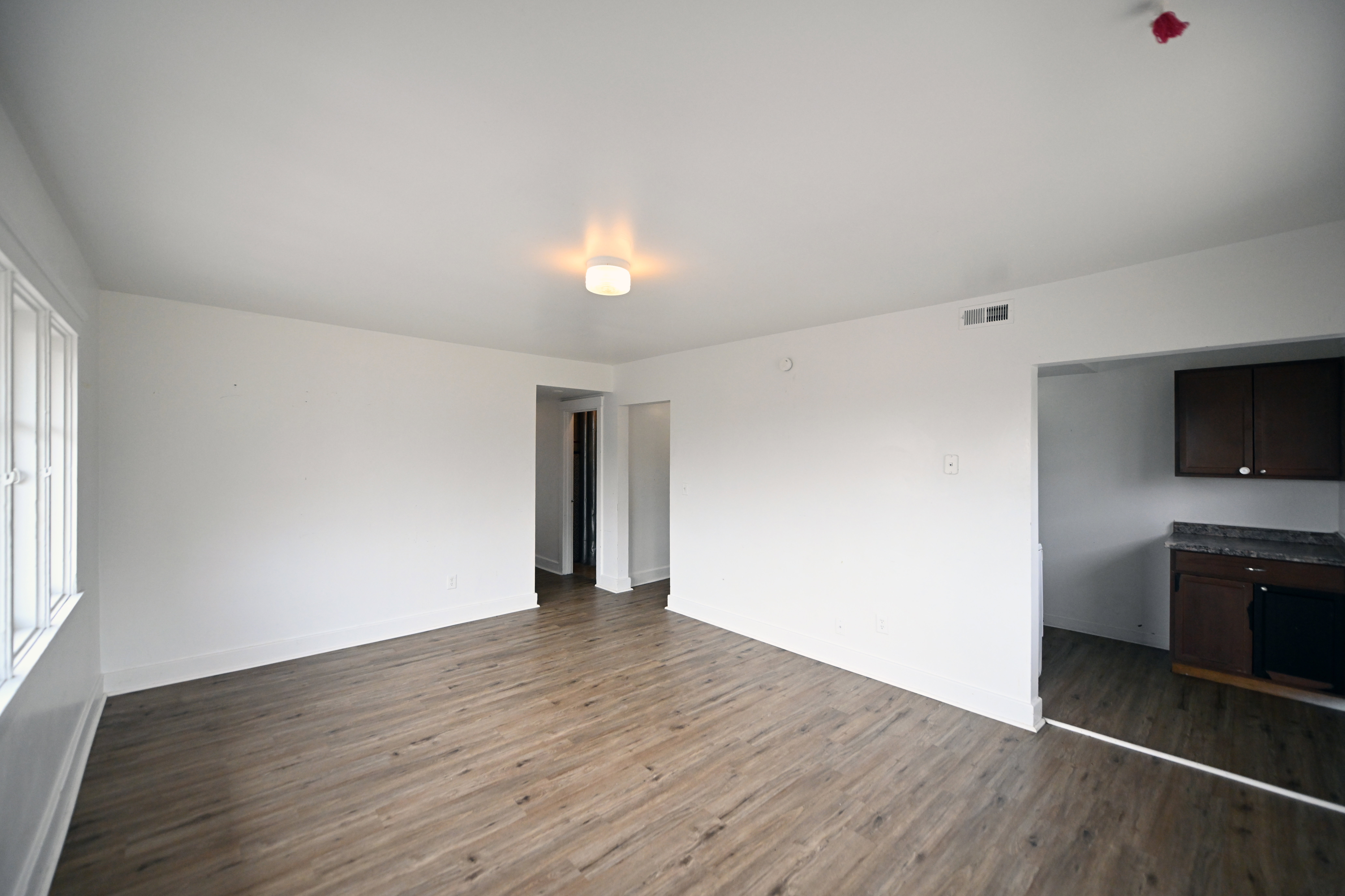 Spacious room with wood-finish flooring, white walls, and a recessed ceiling light fixture