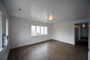 Spacious room featuring wood-finish flooring, white walls, and multiple windows allowing natural light