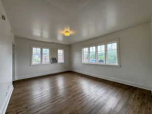 Spacious room featuring wood-finish flooring, white walls, and a multi-pane window configuration