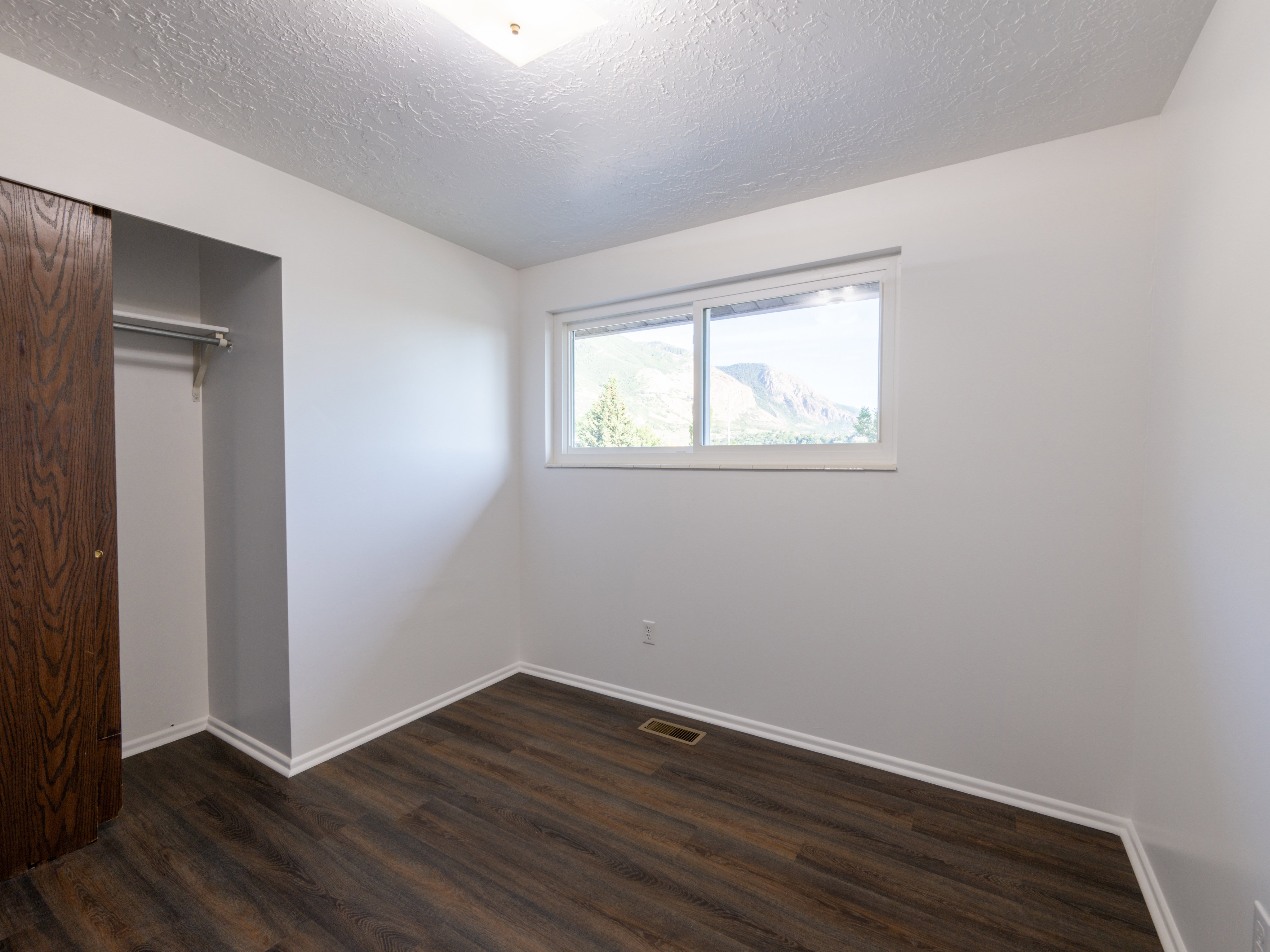 Room featuring rich wood-finish flooring and crisp white walls